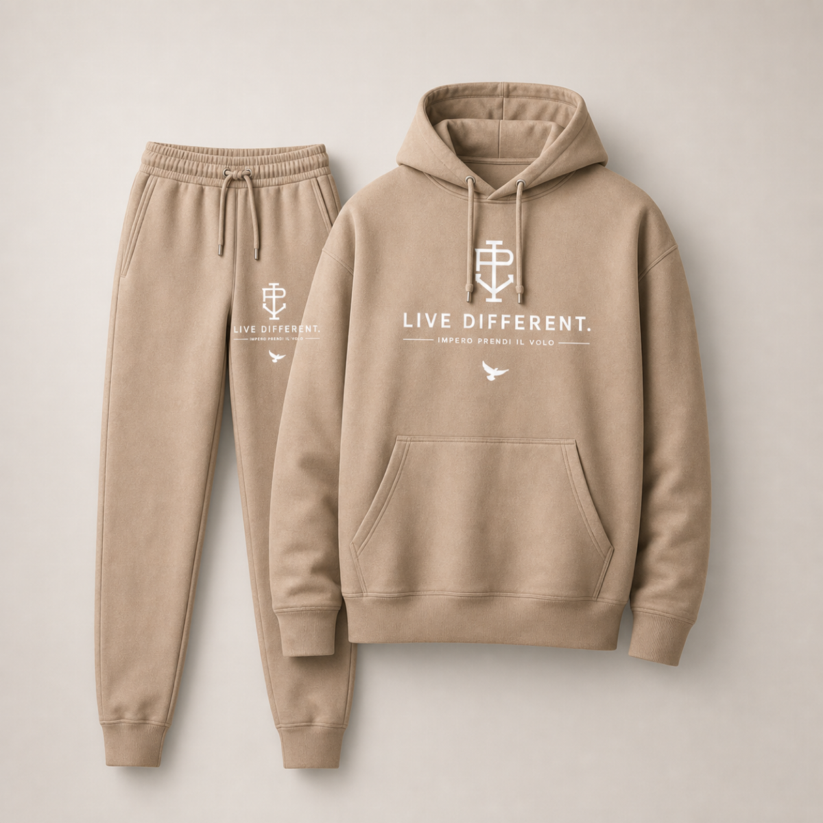 A matching beige hoodie and jogger sweatpants set with white printed graphics on a light beige background. The hoodie features a front kangaroo pocket, drawstring hood, and a white chest print reading 'LIVE DIFFERENT.